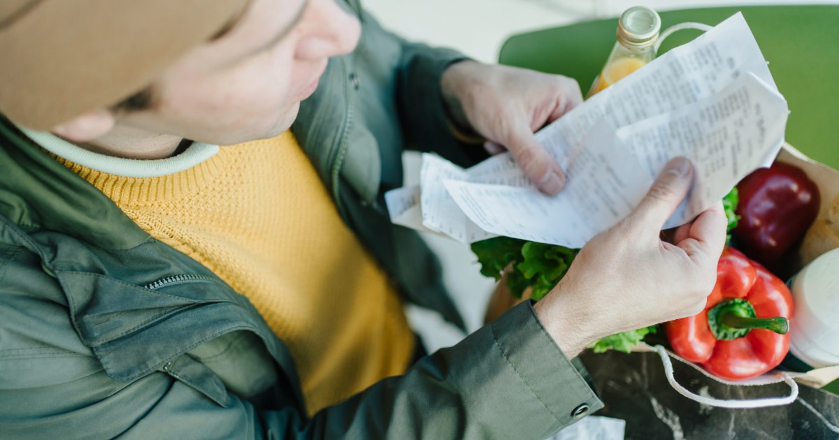 Man looking over his grocery shopping receipt