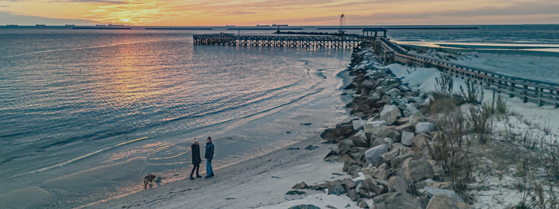 couple walking along water at sunset