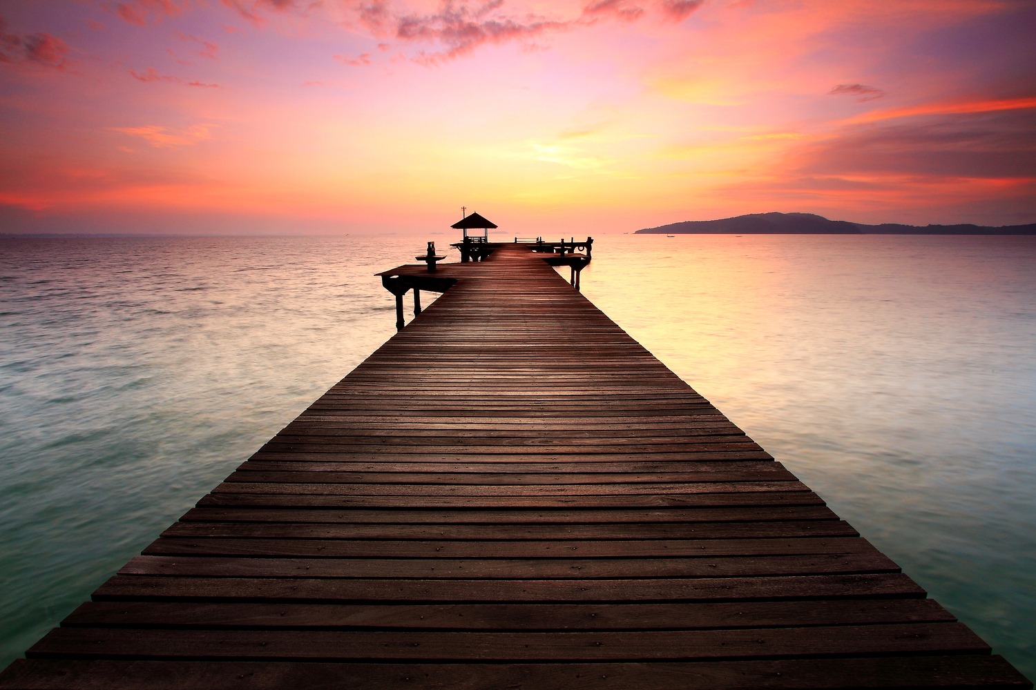Dock leading out to the ocean at sunset