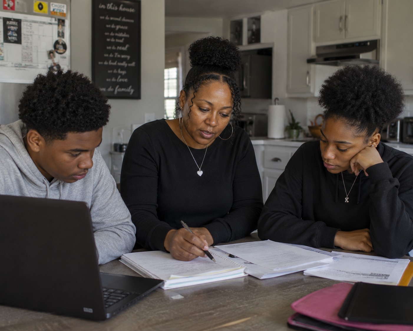 A stay-at-home mom reviews paperwork at the kitchen table with her two teenage children