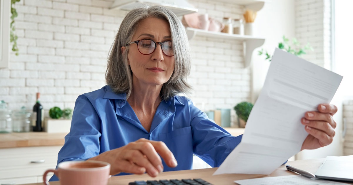 Woman assessing her retirement plan while reviewing paperwork in her kitchen