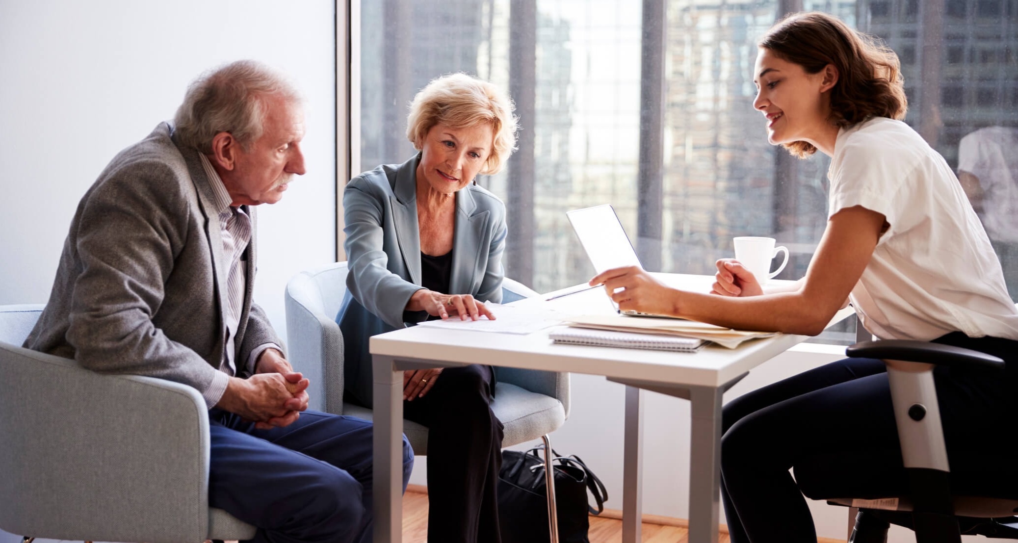 Senior couple sitting with an advisor discussing documents