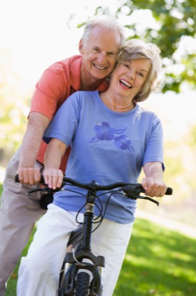 Older couple laughing while riding a bycicle together