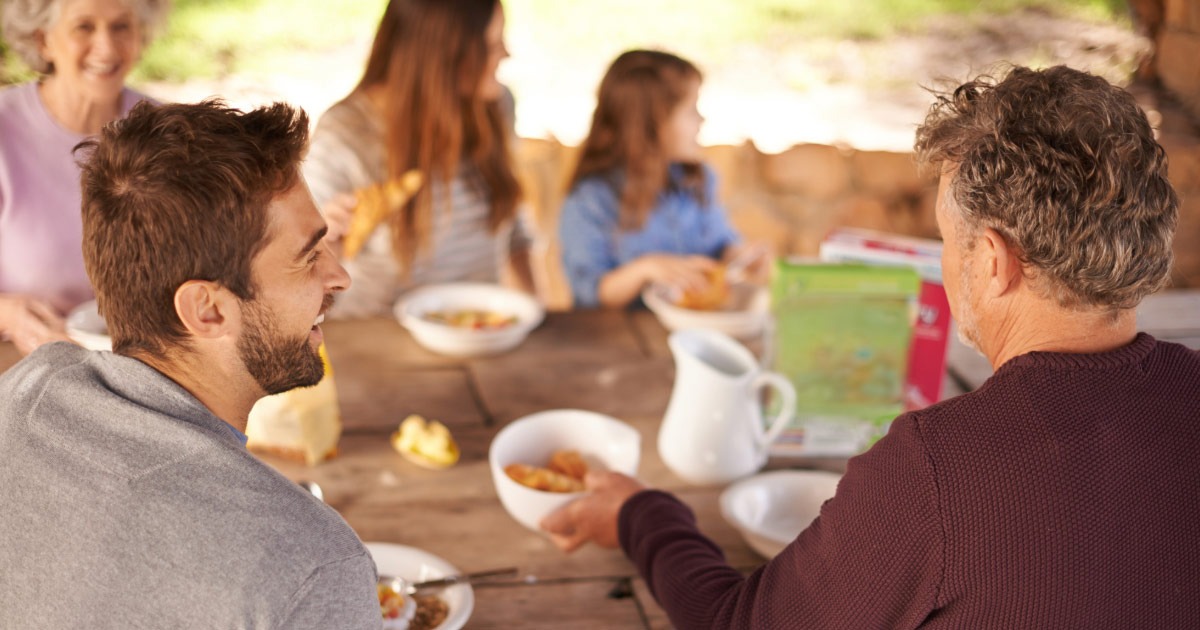 Three generations of a family eating meal outdoors