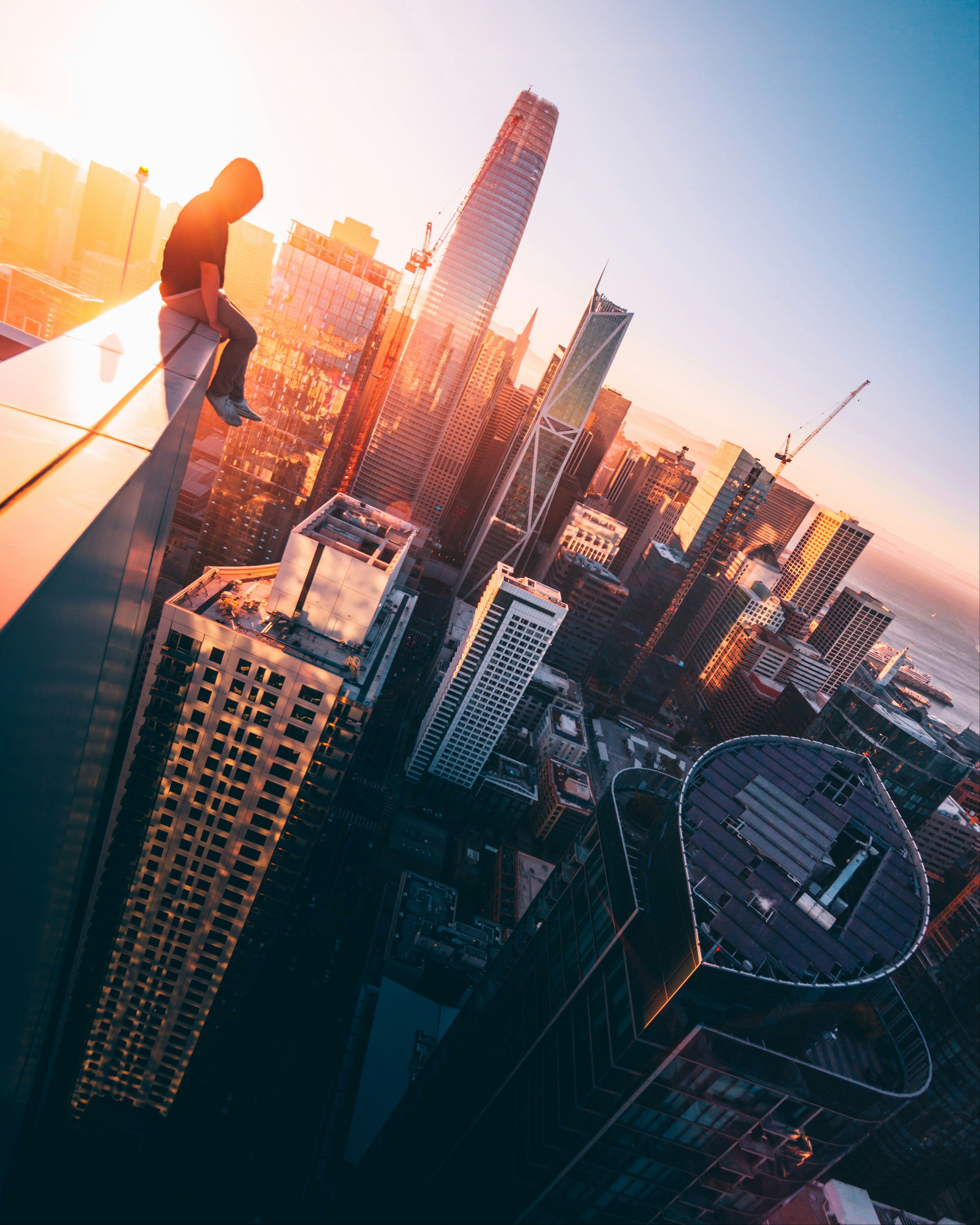 person sitting on the ledge of a tall building