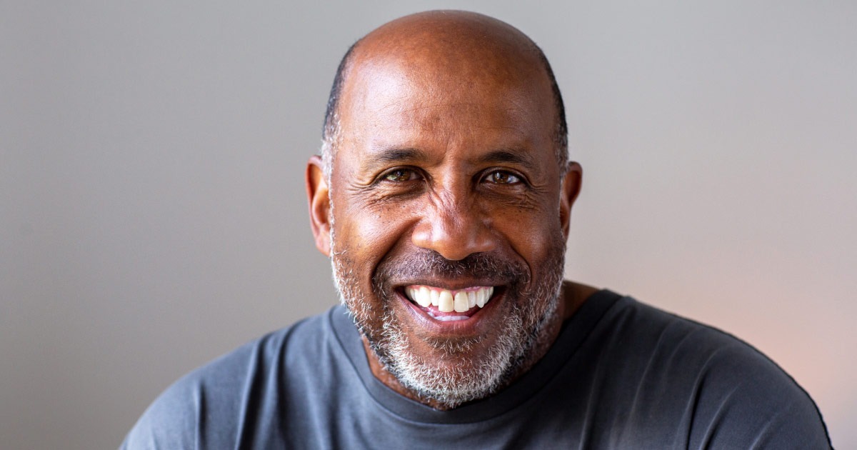 Older man wearing grey shirt smiling for the photographer