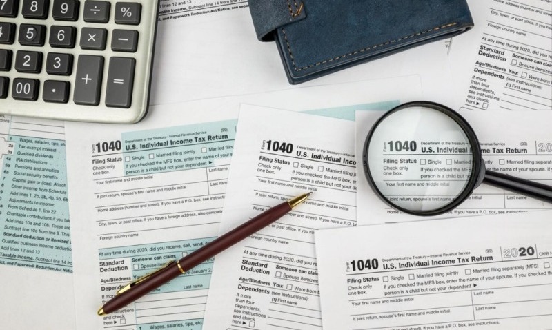 Tax forms with pen, magnifying glass and calculator