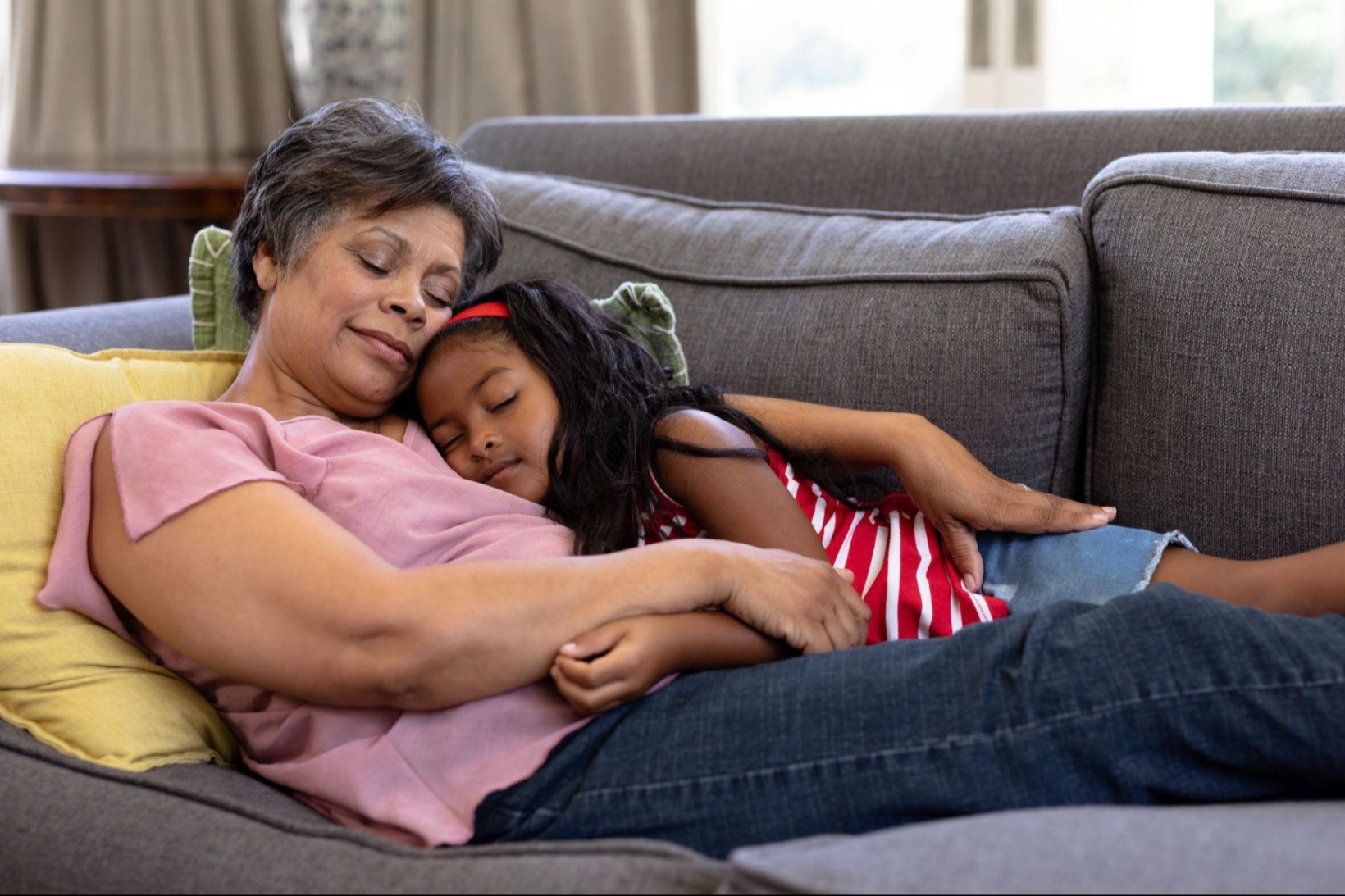 Grandmother embracing her granddaughter on a living-room sofa