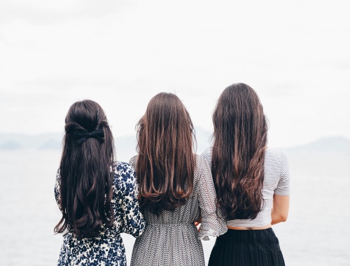 Three women standing together looking out over the water, seen from behind, illustrating financial planning for divorced women.