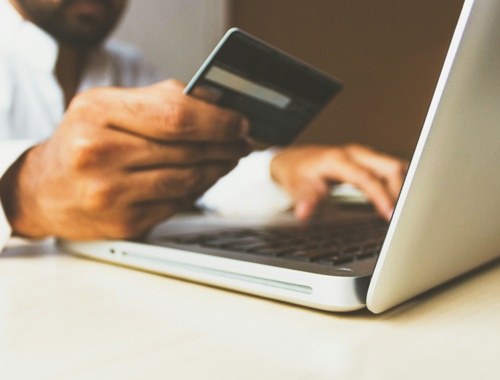 A person holding a bank card while using a laptop, working with a financial advisor for inheritance.