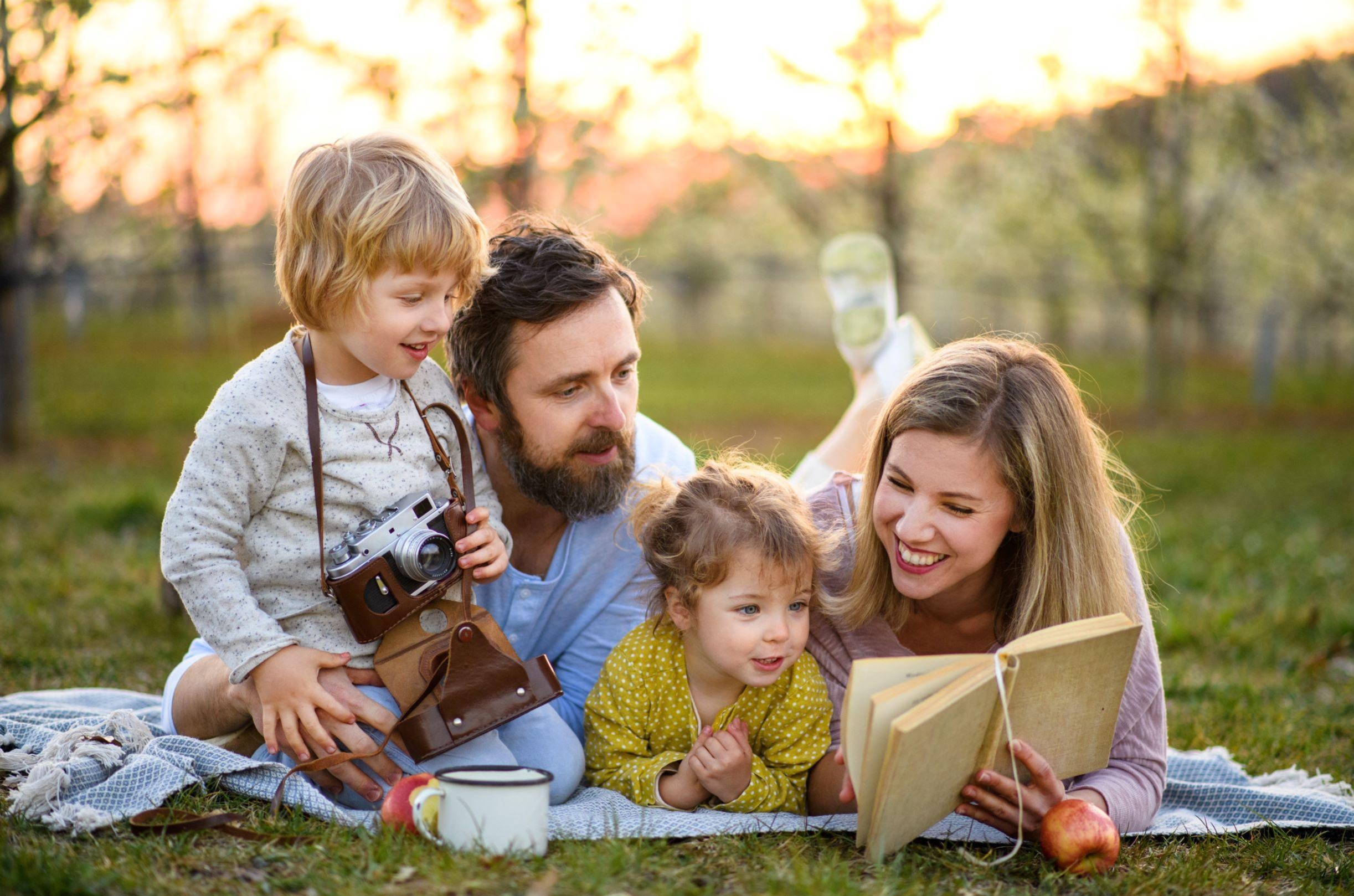 Family reading together outside on a blanket