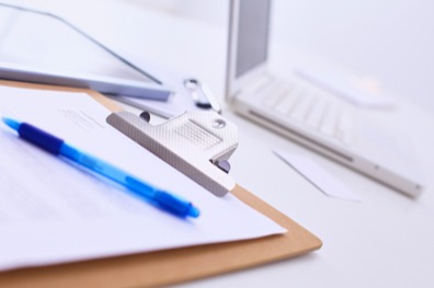 Close-up of a clipboard and laptop