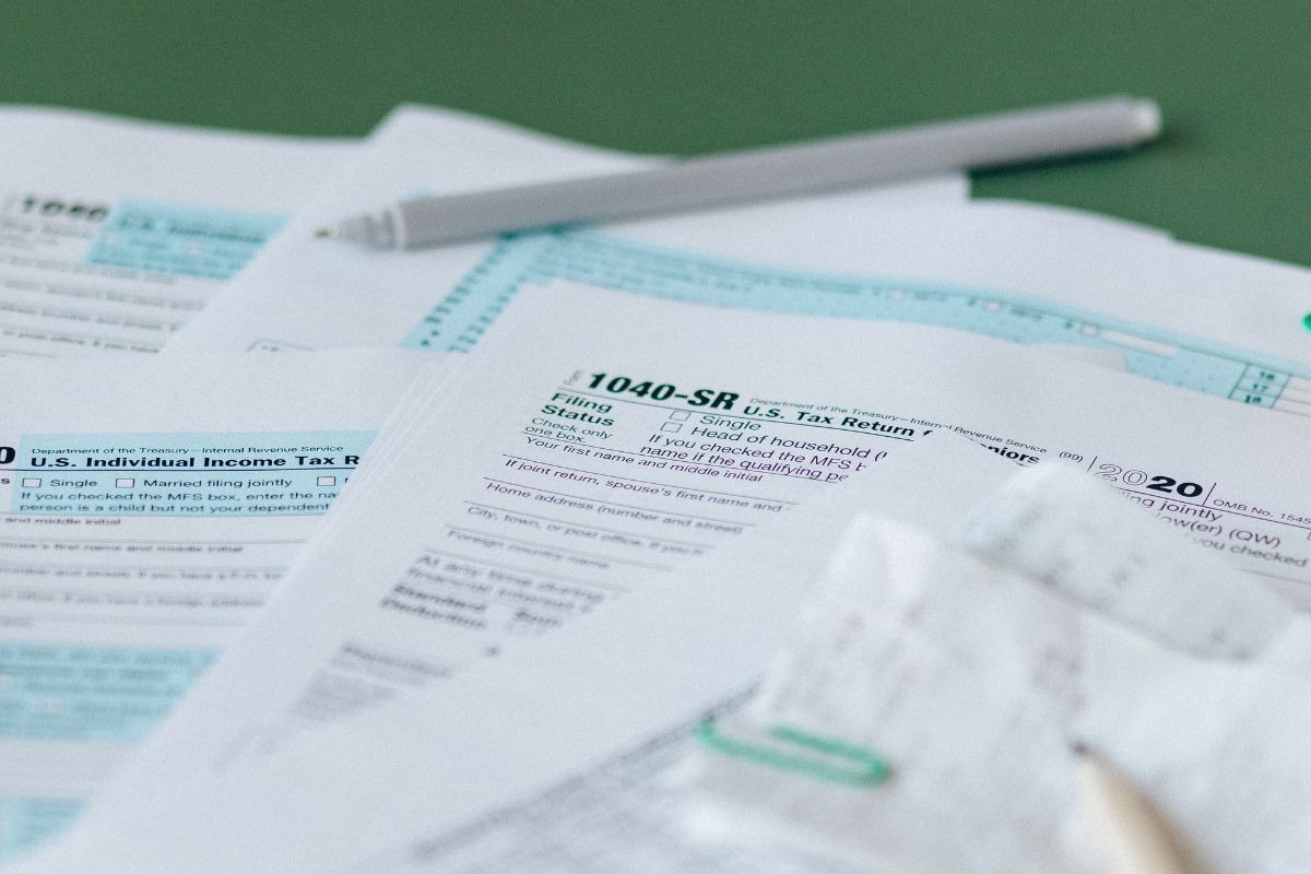 tax papers on green desk with pen on top