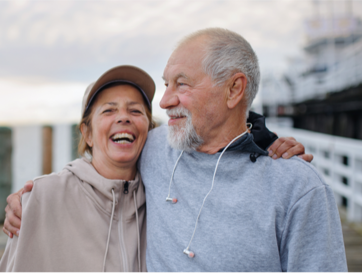 Two people hugging under a grey sky near a dock
