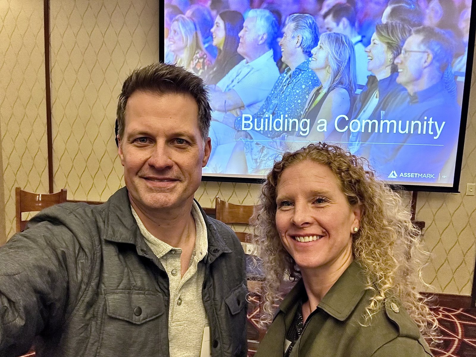 Neill and Nisha smiling in front of a presentation slide reading Building a Community