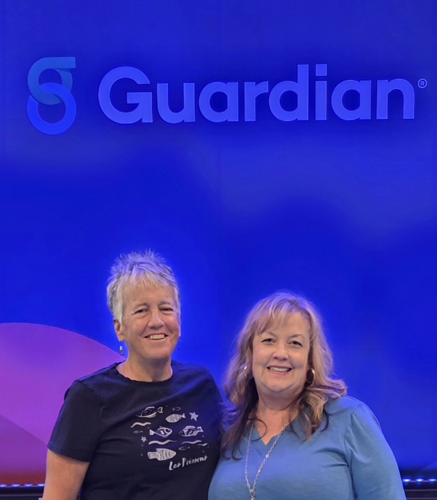 Karen and Melissa standing together in front of a large illuminated Guardian sign