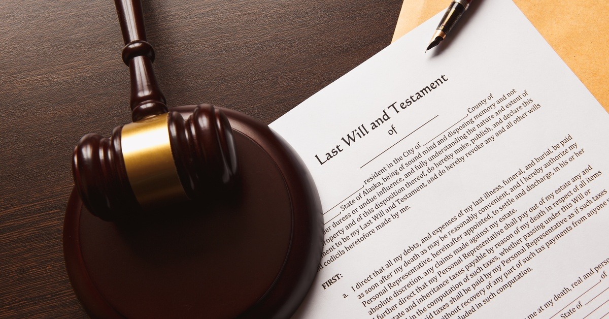 A piece of paper titled 'Last Will and Testament' sitting under a judge's gavel and a fountain pen.