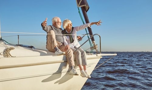 older couple sitting on the edge of a fancy boat in the water