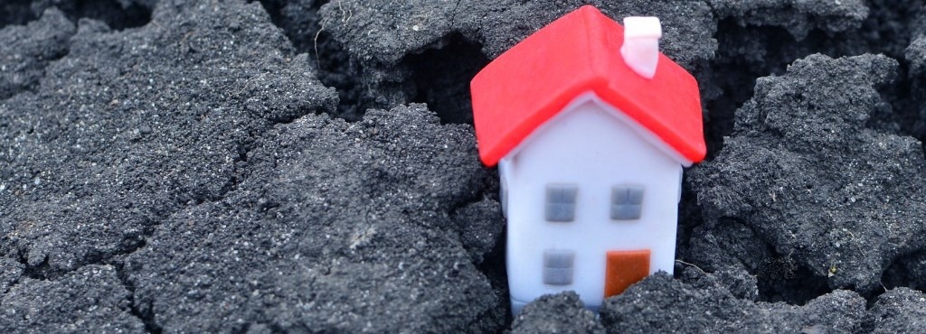 A tiny plastic house sitting on asphalt severely cracked concrete