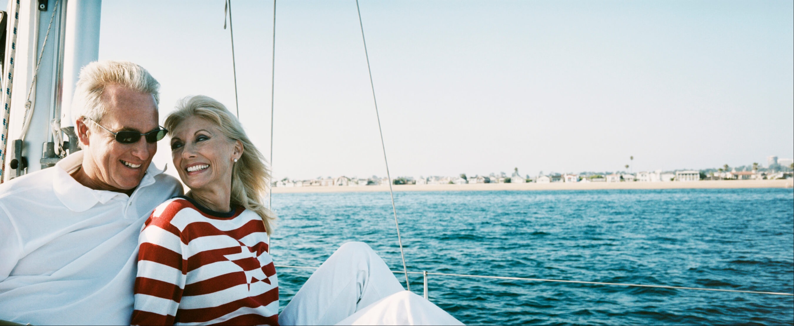 Mature couple on a yacht, embracing travel and adventure after the man’s move back to Canada, reassured that their cross-border retirement planning keeps their finances secure.