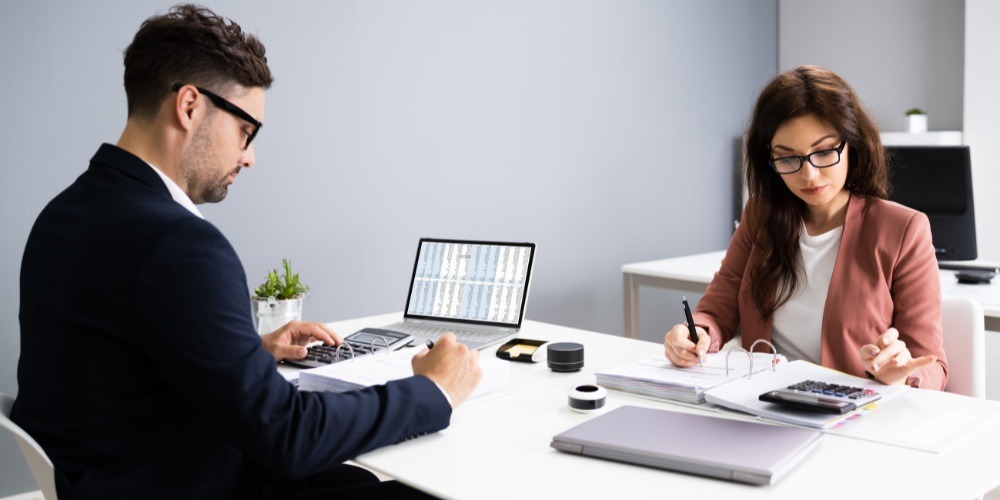 a person working on financial documents and a laptop