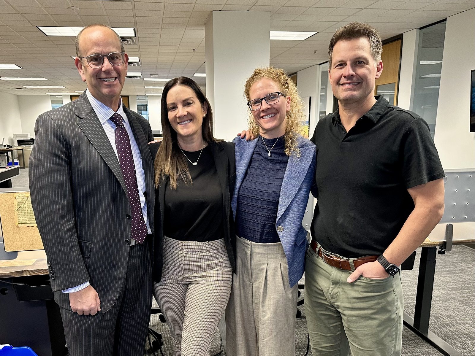 Four people standing together in an open-plan office