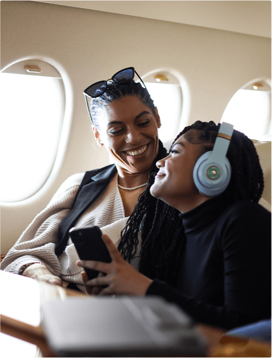 Mother and daughter smiling while traveling on plane