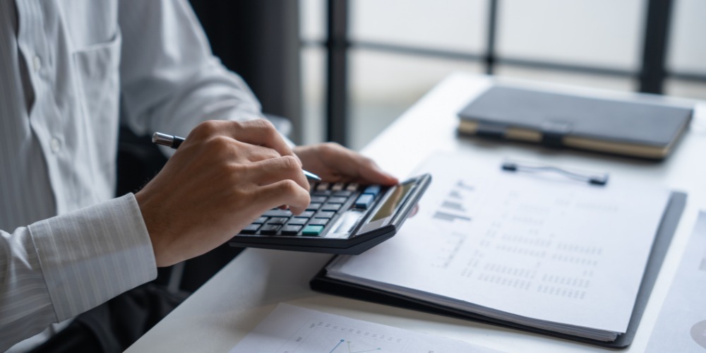 Person using a calculator while reviewing financial documents
