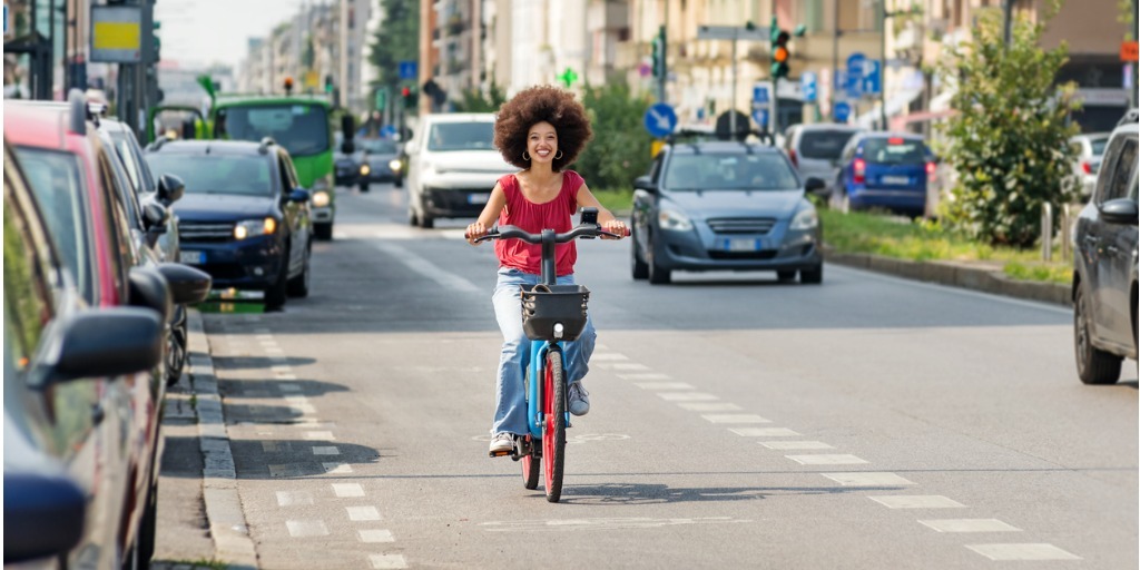 Photo of a women riding an electric bike on a somewhat busy city street.
