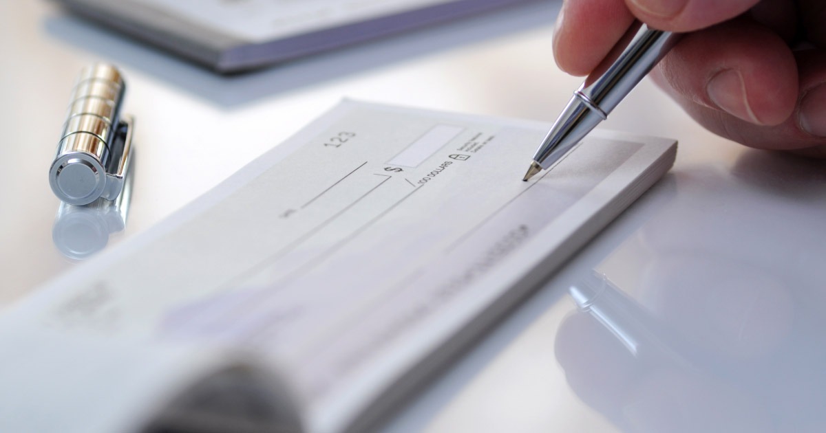 Up close picture of man writing out a check