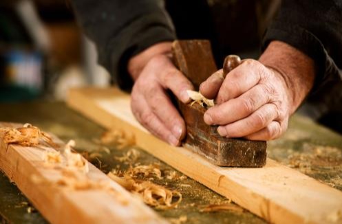 Carpenter using tools to smooth and level wood