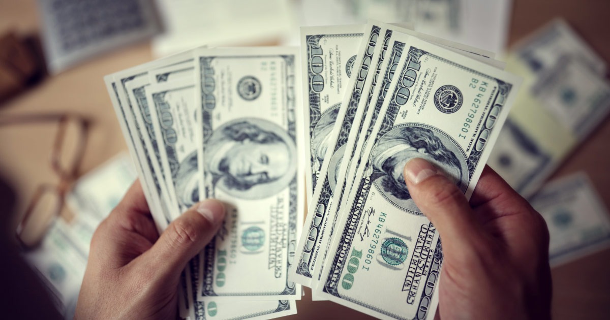 Close up picture of hundred dollar bills being counted by hand