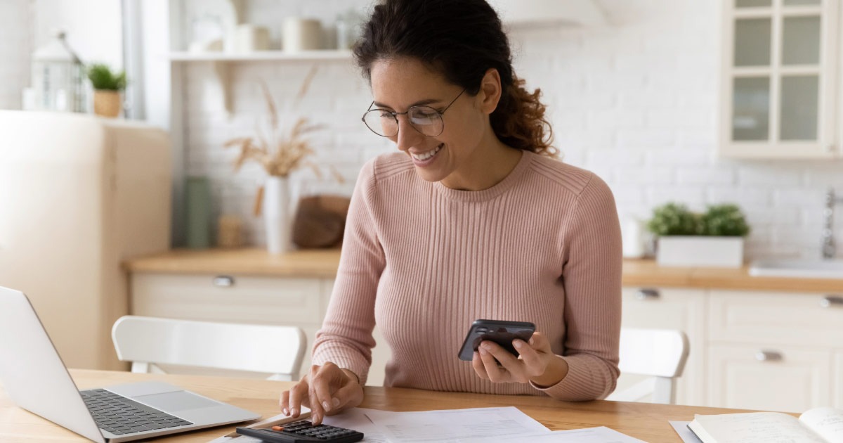 Middle-aged woman in her kitchen calculating financial savings for retirement