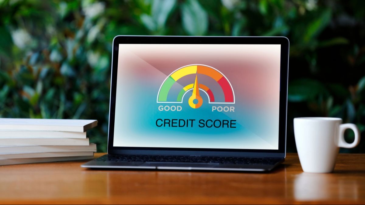 Laptop displaying a credit score gauge with the needle in the 'fair' range. | GOOD POOR CREDIT SCORE