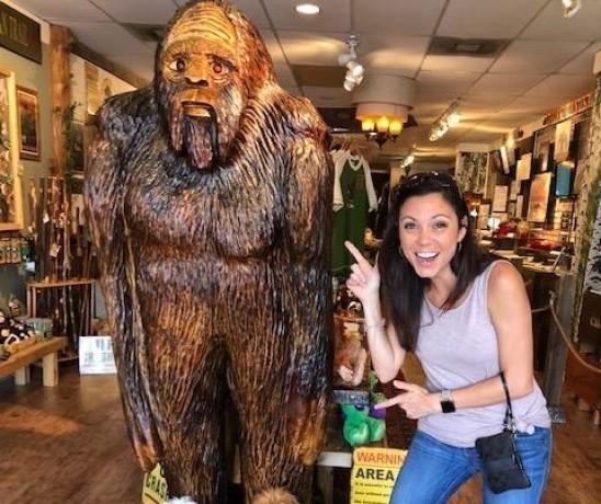 Nicole stands beside a large Bigfoot statue, smiling and posing for the camera.
