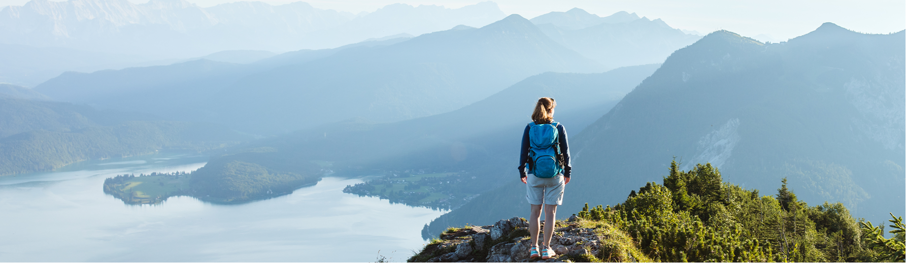 Women standing on the peak of a mountain overlooking a lake