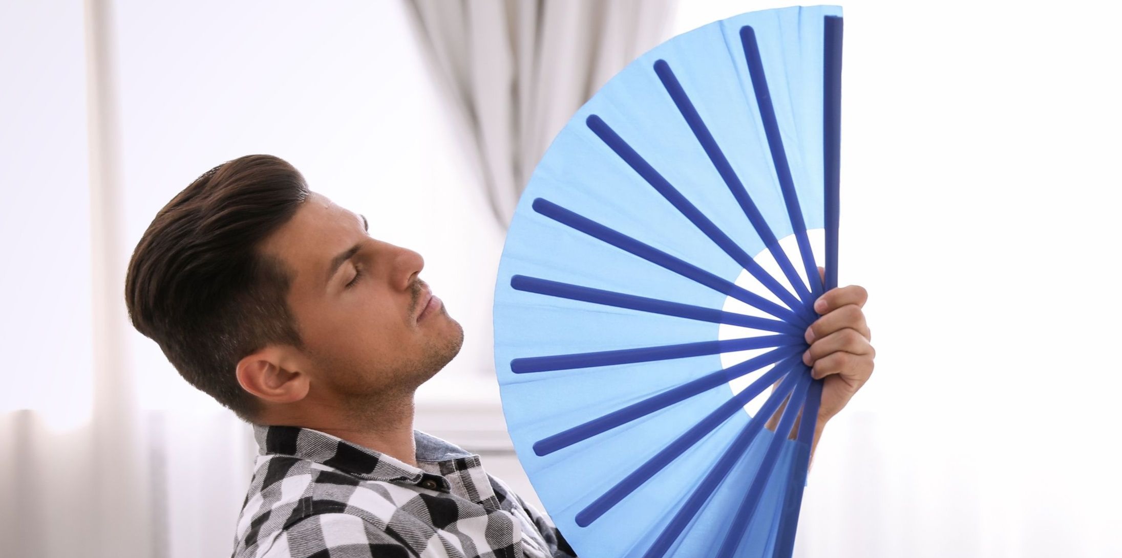 Photo of a man fanning himself with a blue handheld folding fan