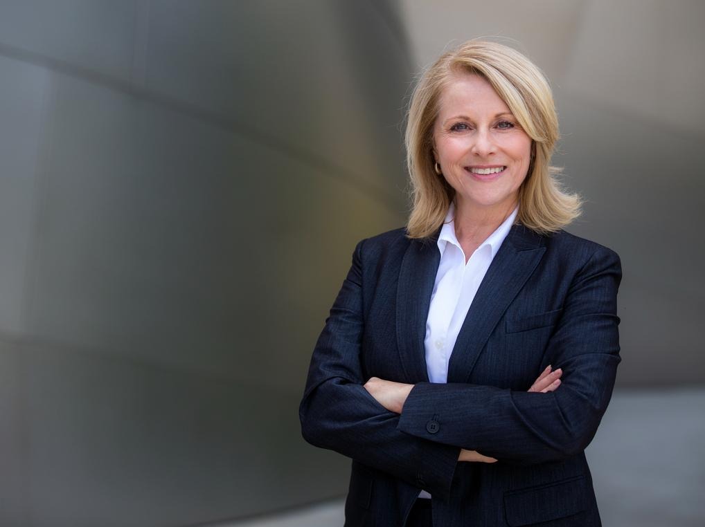 Woman in a business suit smiling with her arms crossed