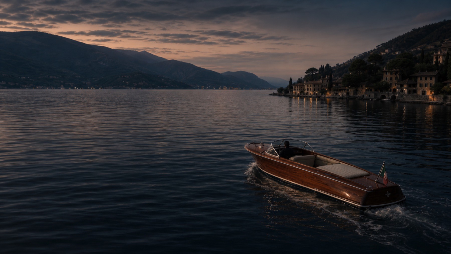 A classic wooden runabout crossing a calm Italian Riviera bay at dawn