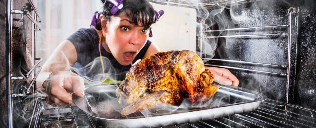 Photo of distressed women pulling slightly burnt turkey out of oven