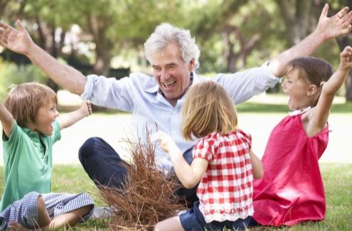 Grandfather teaching grandchildren to build a camp fire