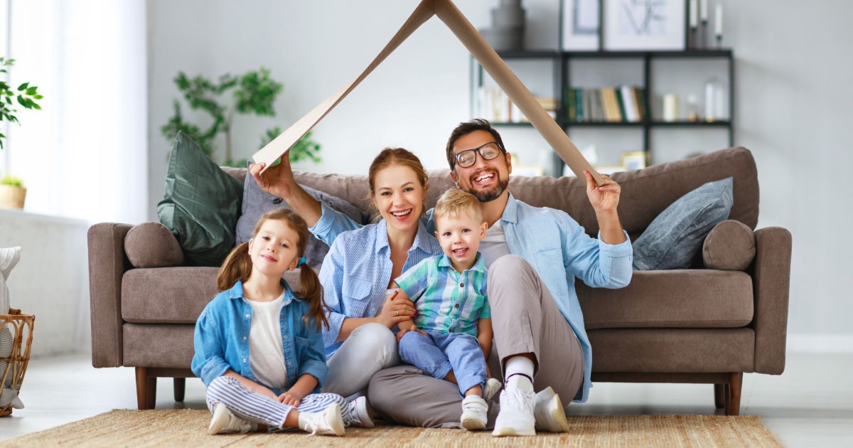 Man holding carboard box roof over wife and daughters heads