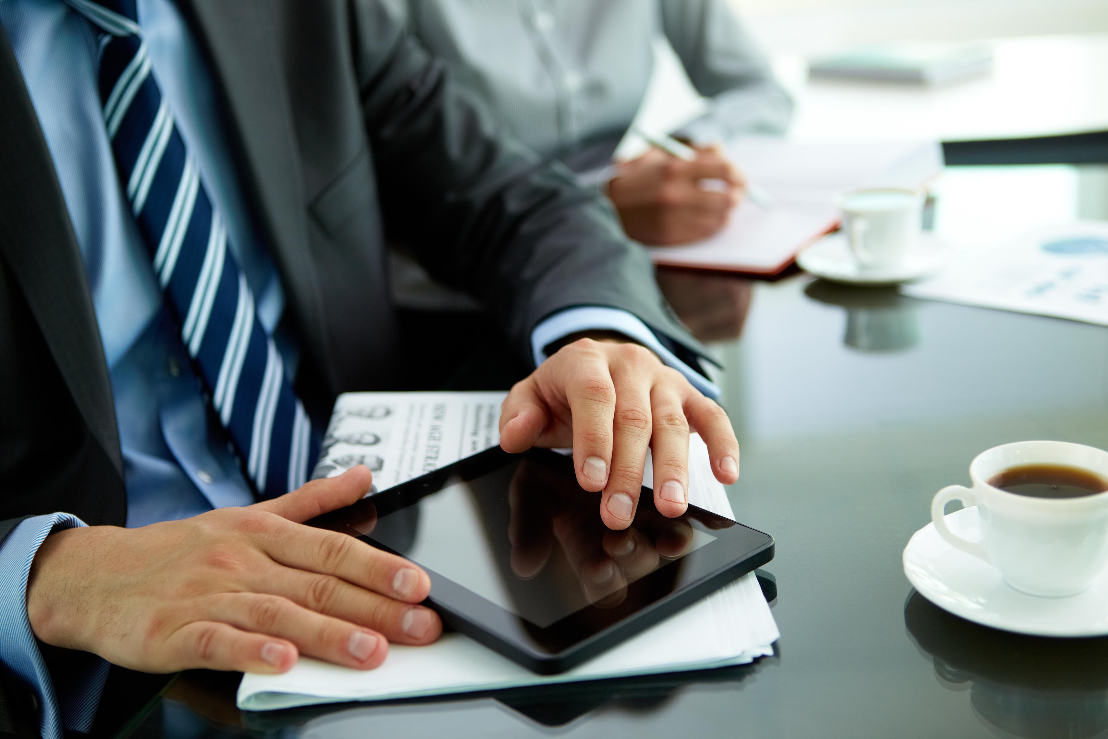 Close-up of a businessman with a newspaper, cup of coffee and a tablet