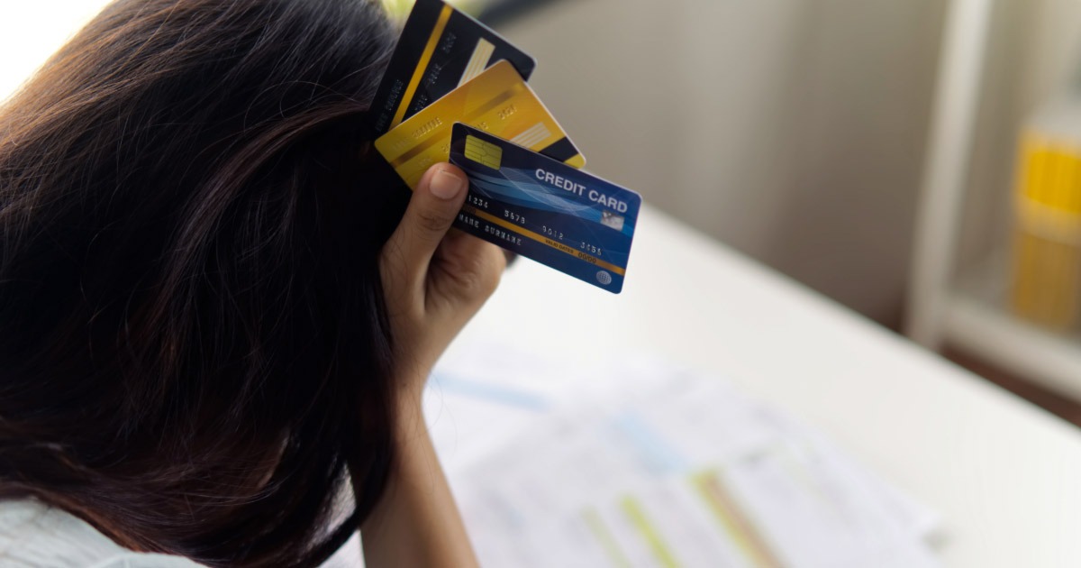 Woman holding credit cards up to her head in frustration