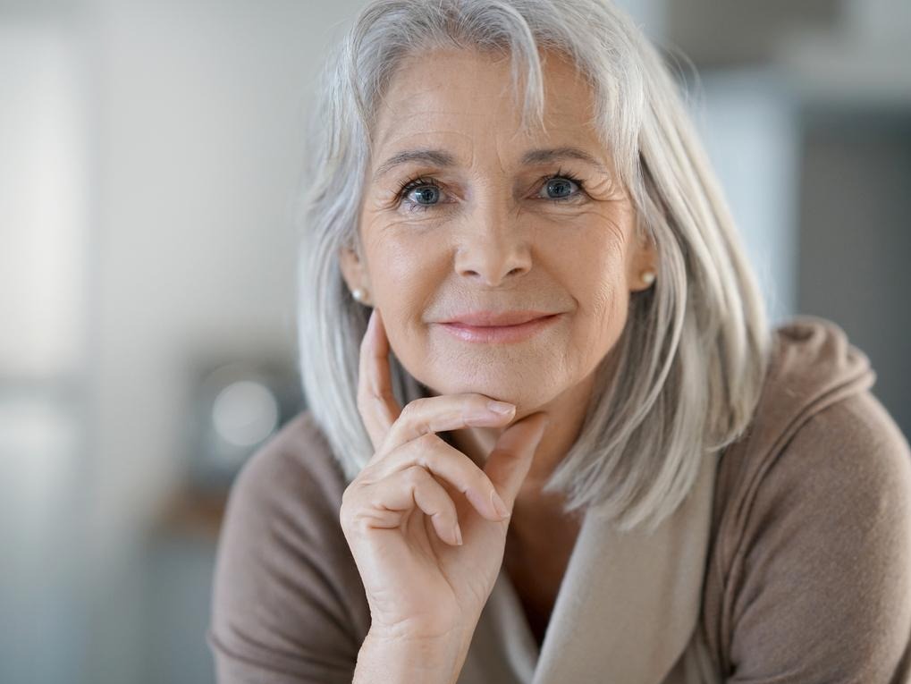 Woman with long white hair with her chin resting on her fingers and smiling