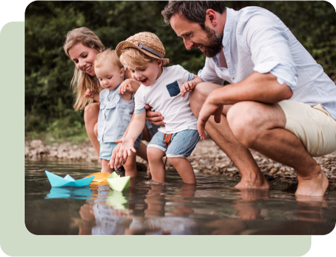 Family playing with paper boats in a stream