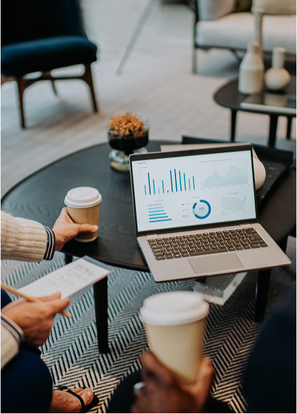 two collegeaus discussing chart on computer over coffee