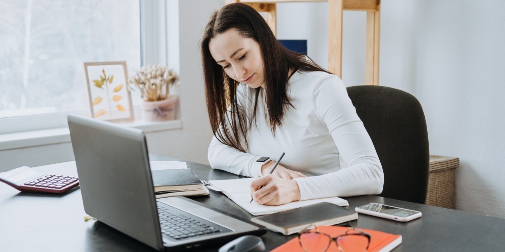 Woman writing in a notebook at her desk
