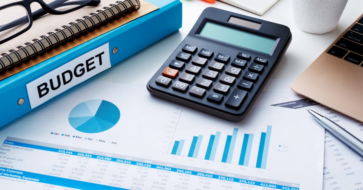 Desktop with budgeting folder, calculator, and charts