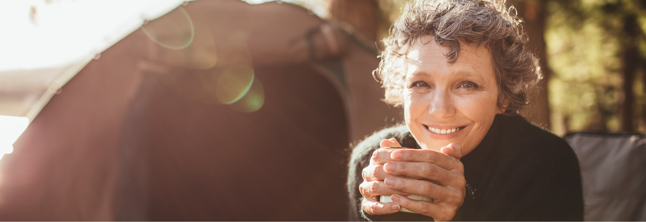 woman smiling and holding a warm beverage